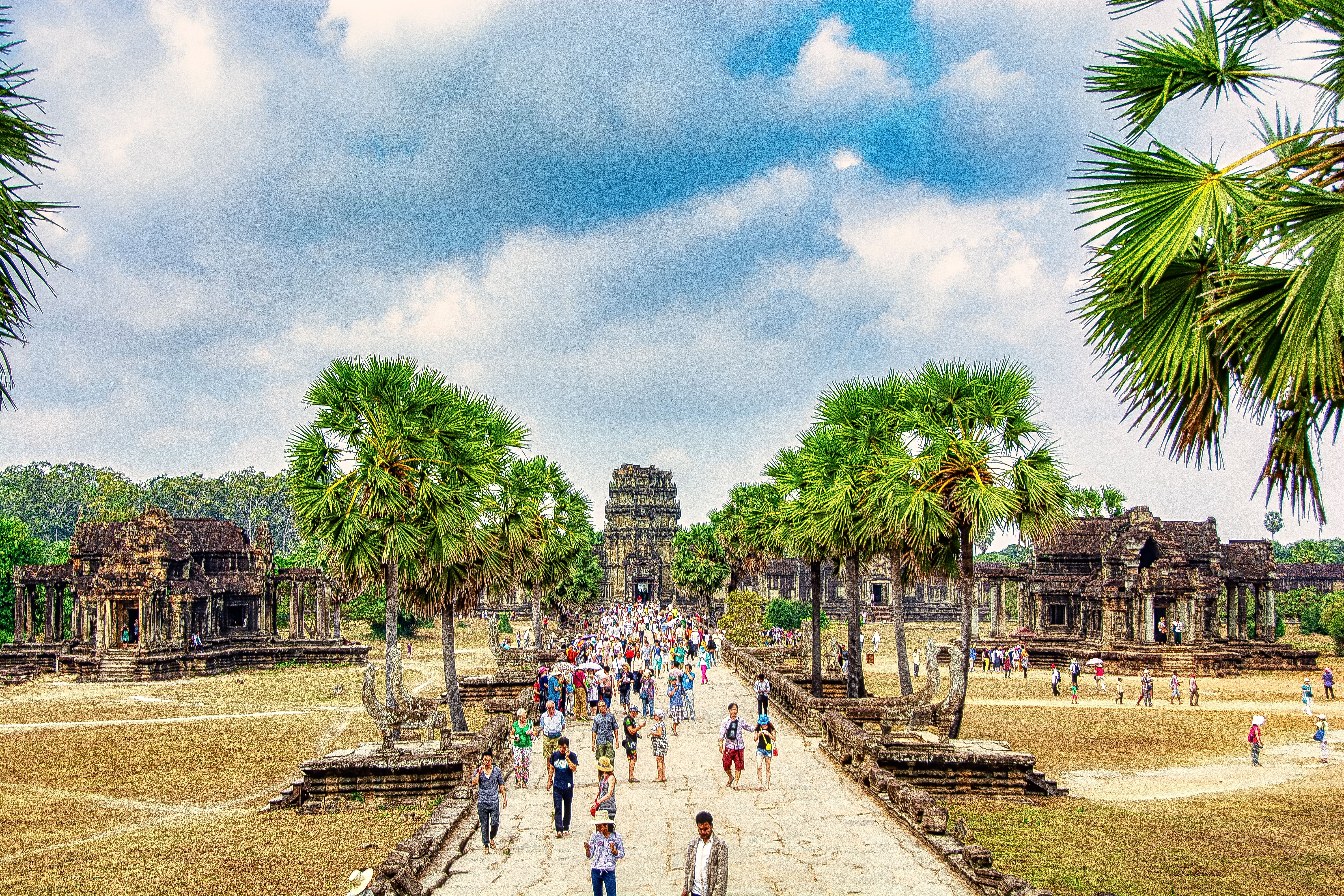 Tourists explore the iconic Angkor Wat in Siem Reap, Cambodia, under a bright sky.